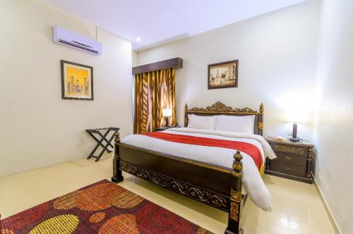 a bedroom with a king sized bed and a night stand at Hotel One Bahawalpur in Bahawalpur