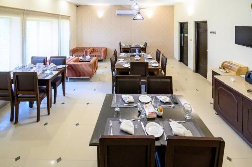 a dining room with tables and chairs and a couch at Hotel One Bahawalpur in Bahawalpur