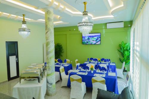 ein Raum mit blauen Tischen und weißen Stühlen und Kronleuchtern in der Unterkunft United Hotel Balessing in Balessing