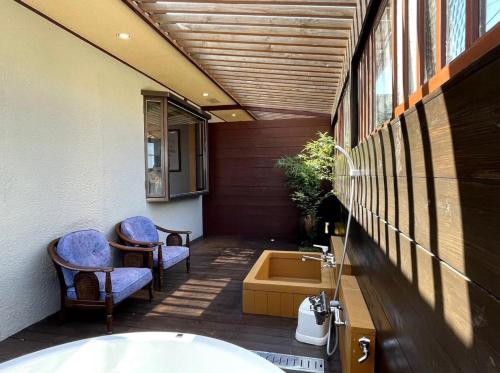 a bathroom with a bath tub and two chairs at 南熱海長浜公園近くバーベキュー可能露天風呂付ゲストハウス in Taga