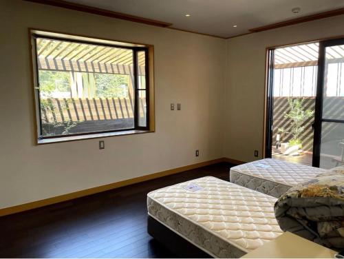 two beds in a room with two windows at 南熱海長浜公園近くバーベキュー可能露天風呂付ゲストハウス in Taga