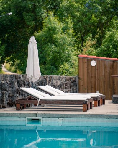 a group of lounge chairs and an umbrella next to a pool at Casa do Marujo e Casa do Mirone in Fornos de Algodres