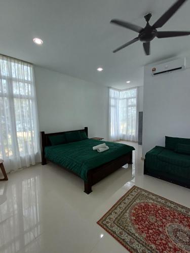 1 dormitorio con cama verde y ventilador de techo en Mengkuang Villa - Family Deluxe Room, en Kampong Mangkok