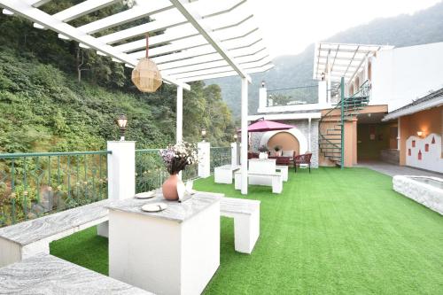 a patio with green grass and a table and chairs at Tiaraa Lite A Ganges Retreat in Shivpuri