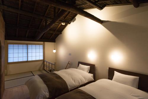 een slaapkamer met 2 bedden en een raam bij Kakishibu an Machiya House in Kyoto