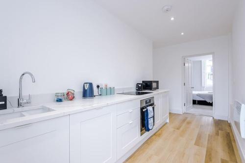 a white kitchen with white cabinets and a sink at Sleeps 6, Stylish Apartment, Perfect For Groups, Long Term Disc in Otley