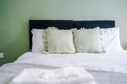 a bed with white pillows and a black headboard at Sleeps 6, Stylish Apartment, Perfect For Groups, Long Term Disc in Otley