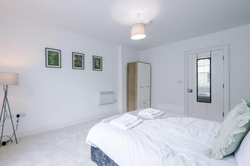 a white bedroom with a bed and a lamp at Sleeps 6, Stylish Apartment, Perfect For Groups, Long Term Disc in Otley