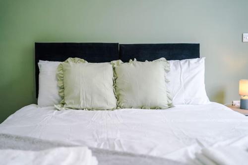a bed with white pillows and a black headboard at Sleeps 6, Stylish Apartment, Perfect For Groups, Long Term Disc in Otley