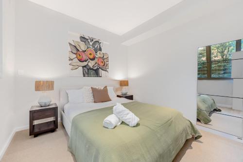 a white bedroom with a bed with towels on it at Modern & Quiet 1BR Apartment with Private Garden in Bondi close to the Beach in Sydney