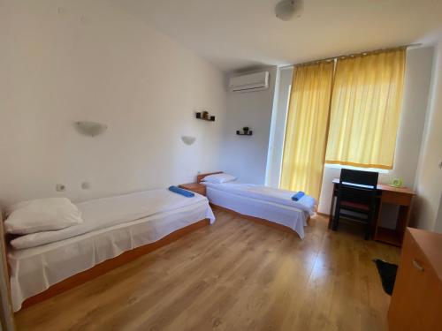 a room with two beds and a desk and a window at BASSO Guest Rooms in Perushtitsa