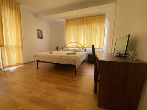 a bedroom with a bed and a desk and a window at BASSO Guest Rooms in Perushtitsa