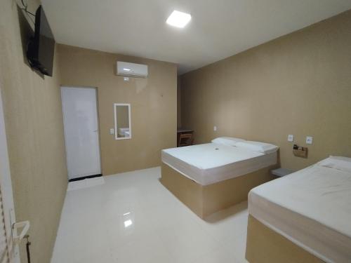 a small room with two beds and a television at Karajas Hotel in Quixeramobim