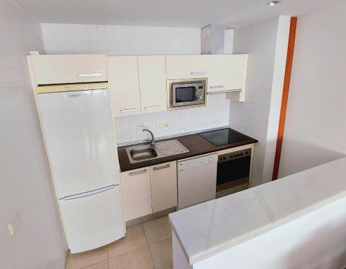 a small kitchen with a white refrigerator and a sink at Domocenter Apartamentos Turísticos in Bormujos