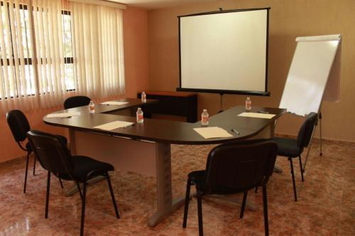 a conference room with a table and chairs and a screen at Hotel Finca Las Hortensias in Tepotzotlán