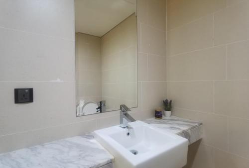 a white bathroom with a sink and a mirror at The Straits Suites by Ciconia in Melaka