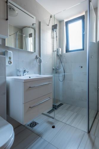 een witte badkamer met een douche en een wastafel bij Konačište Egoiste - Centar in Zlatibor