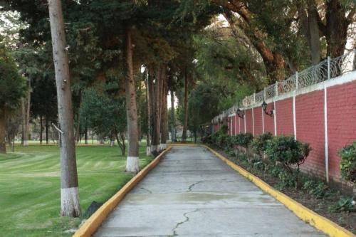 a walkway with trees next to a brick wall at Hotel Finca Las Hortensias in Tepotzotlán
