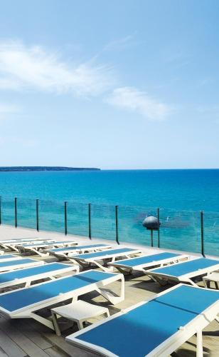 a row of blue and white lounge chairs and the ocean at Hotel Eden Palma Playa Adults Only in Can Pastilla