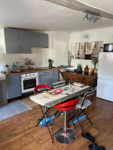 eine Küche mit einem Tisch und 2 roten Stühlen in der Unterkunft Appart 6 couchages en plein cœur de village in Neauphle-le-Château