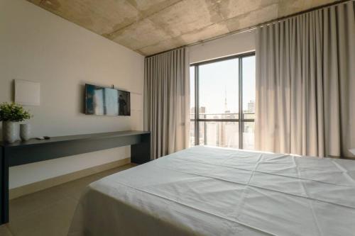 a bedroom with a white bed and a large window at Apartamento Centro Prime CA1404 in Maringá