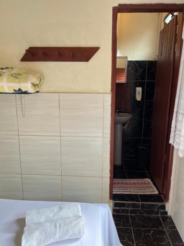 a room with a bed and a bathroom with a sink at Suítes São Judas in Pirenópolis