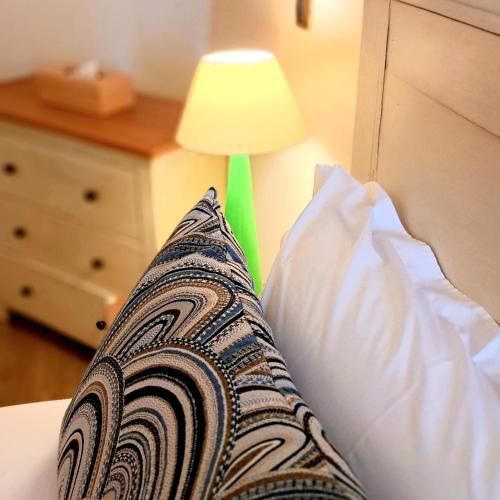 a pillow sitting on a bed next to a lamp at Le Nautile Beachfront in Saint-Gilles les Bains