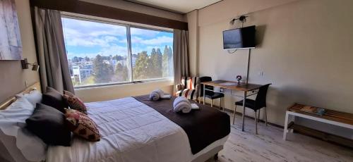 a bedroom with a bed and a desk and a window at Aires de Bariloche in San Carlos de Bariloche
