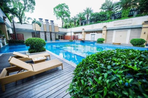 a swimming pool with two lounge chairs and trees at Ramada Plaza By Wyndham Fuzhou South in Fuzhou