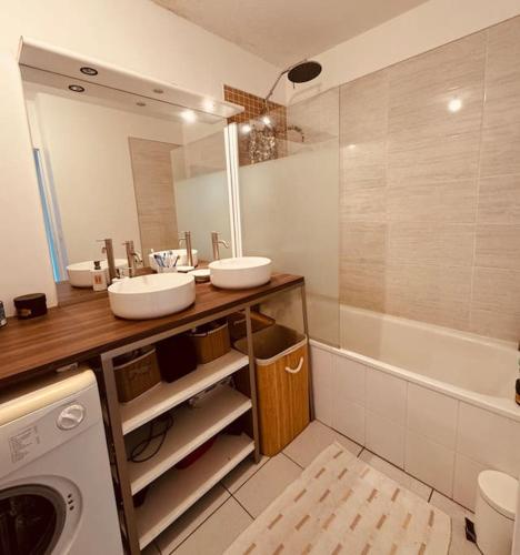 La salle de bains est pourvue de 2 lavabos, d'une baignoire et d'un lave-linge. dans l'établissement Bel appartement proche Mulhouse - grand balcon 9m2, à Pfastatt