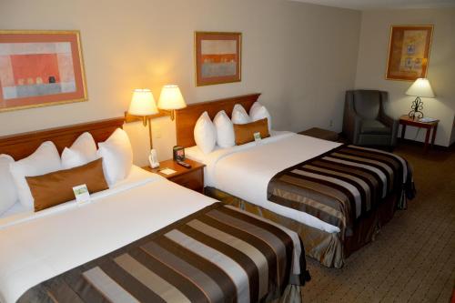 a hotel room with two beds and a chair at Wingate by Wyndham West Monroe in West Monroe