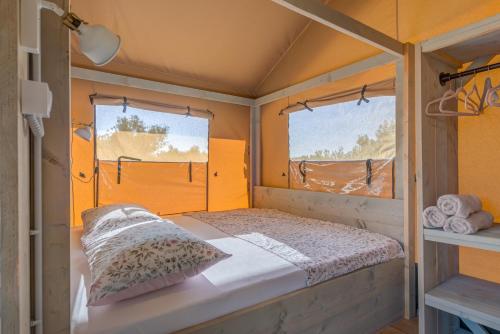 ein kleines Zimmer mit einem Bett und zwei Fenstern in der Unterkunft Adriatic Heritage Glamping No1 with Jacuzzi in Maslinica