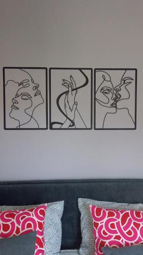 four framed pictures on a wall above a bed at Novecento in Bertinoro