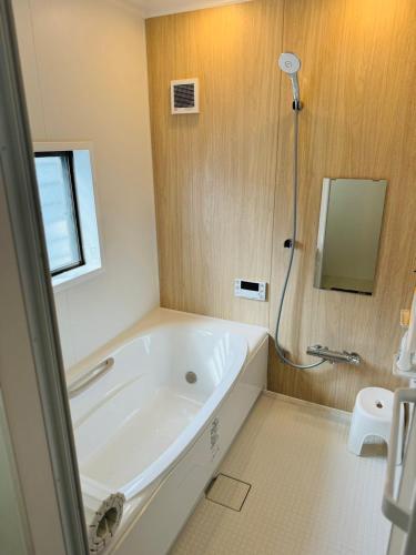 a white bathroom with a tub and a shower at にいのうみ in Tosa