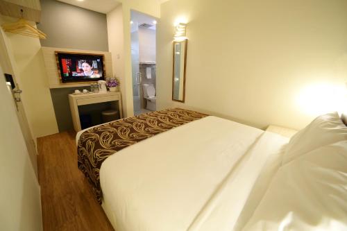 a hotel room with a bed and a tv at Rimba Hotel in Kuala Terengganu