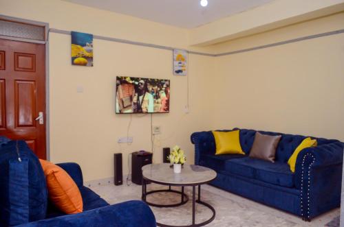 a living room with a blue couch and a table at Ela Stays Nyahururu in Nyahururu