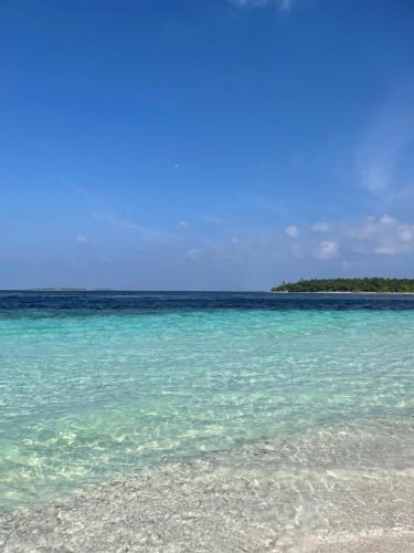 a beach with blue water and an island in the distance at Kendhoo holidays in Kendhoo