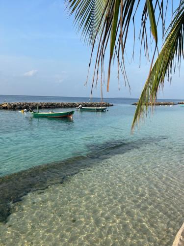 a beach with two boats in the water at Kendhoo holidays in Kendhoo