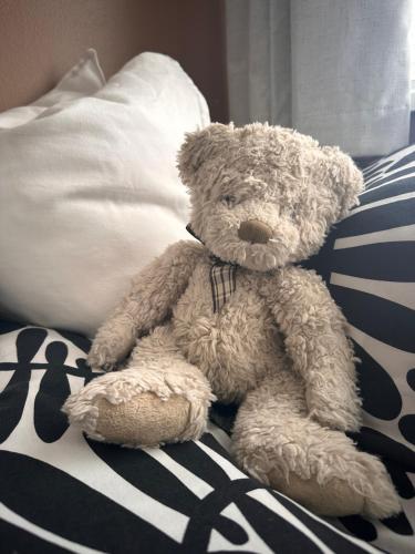 a brown teddy bear sitting on a bed at Everythings Rosey on Rosecroft in Ormskirk