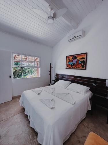 a white bedroom with a large bed with white sheets at Chalés Mariolinha in Ilhabela