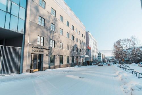 a street covered in snow next to a building at Forenom Aparthotel Jyväskylä in Jyväskylä