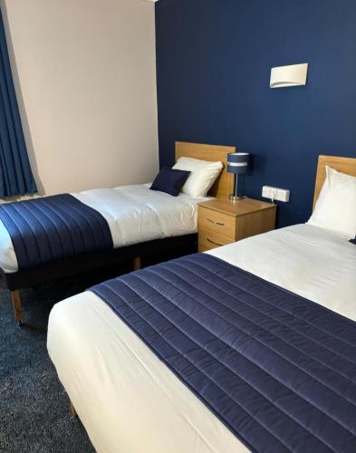 a hotel room with two beds with blue walls at Britannia Hotel Wigan in Standish