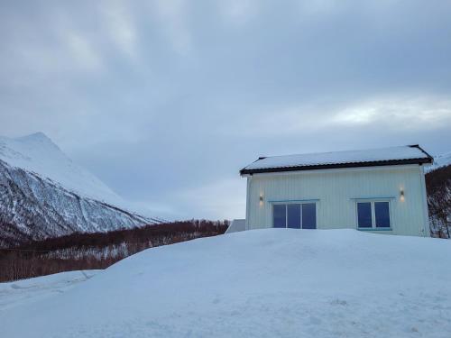 a white building in the snow next to a mountain at Malangen Lodge in Tromsø