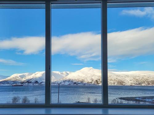 a view of snow covered mountains from a window at Malangen Lodge in Tromsø