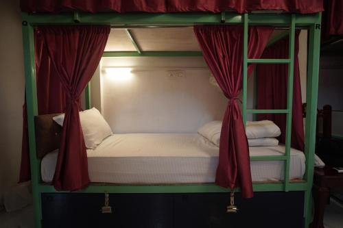 a double bunk bed with red curtains and white sheets at Hostel Funky Bunky in Udaipur