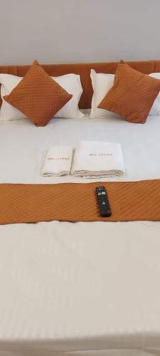 a bed with pillows and a remote control on it at Hotel Kapish International Solapur 400 mts from Bus Stand and 500 mtr from railway station in Solapur