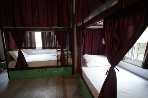 two bunk beds in a room with red curtains at Hostel Funky Bunky in Udaipur