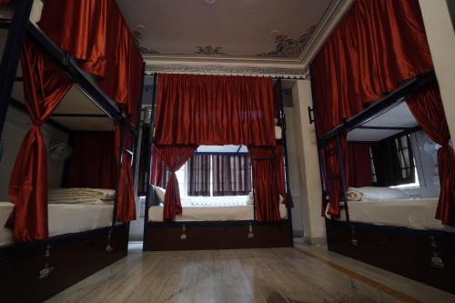 a bedroom with two bunk beds with red curtains at Hostel Funky Bunky in Udaipur
