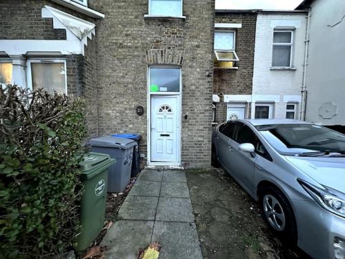 a car parked in front of a house with a white door at the quite one in London