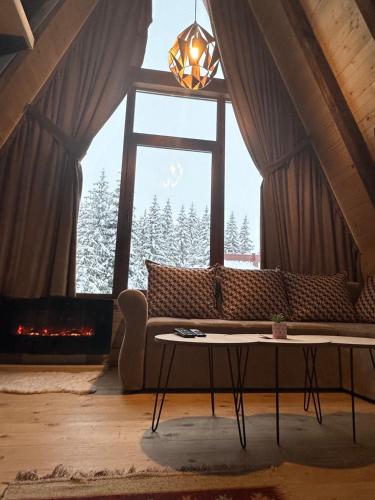a living room with a couch and a large window at Mountain Houses Emilija in Žabljak